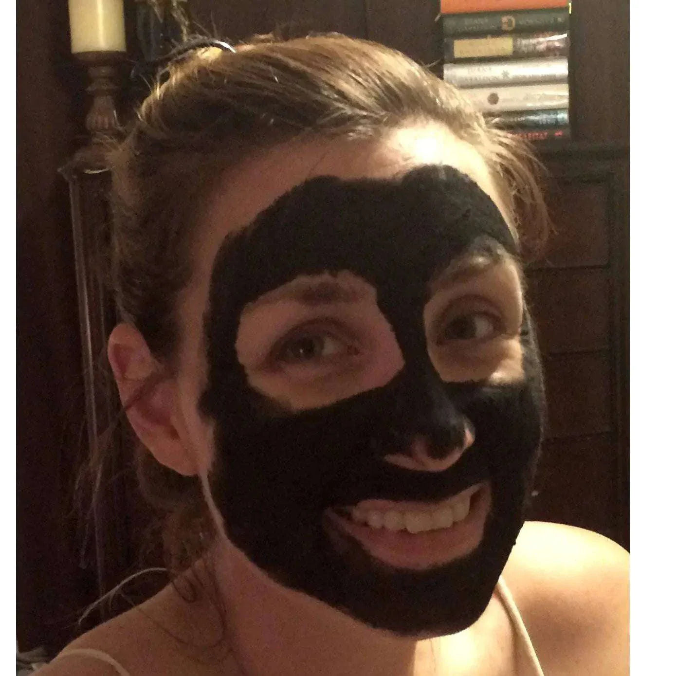 Woman smiling with organic activated charcoal face mask applied for detox and purification