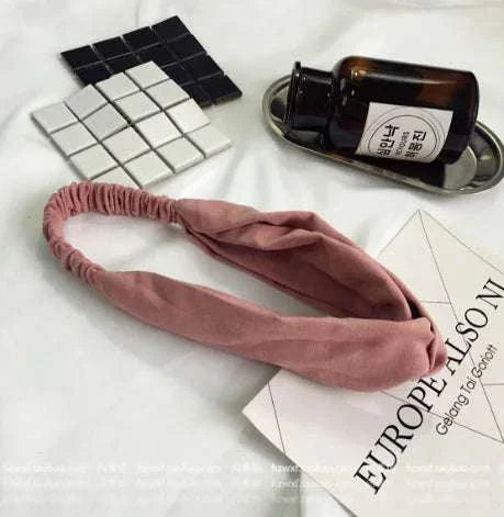 Pink suede hairband hair accessory on white surface with decorative items