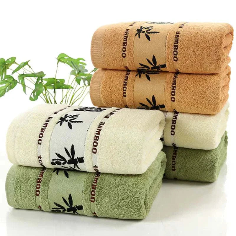 Stack of thick bamboo fiber towels in khaki, green, and white colors with bamboo leaf patterns and natural antibacterial properties
