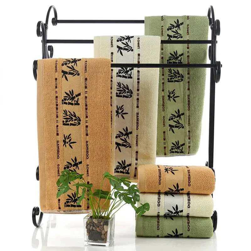 Set of thick bamboo fiber towels in khaki, green, and white with bamboo pattern on black metal towel rack