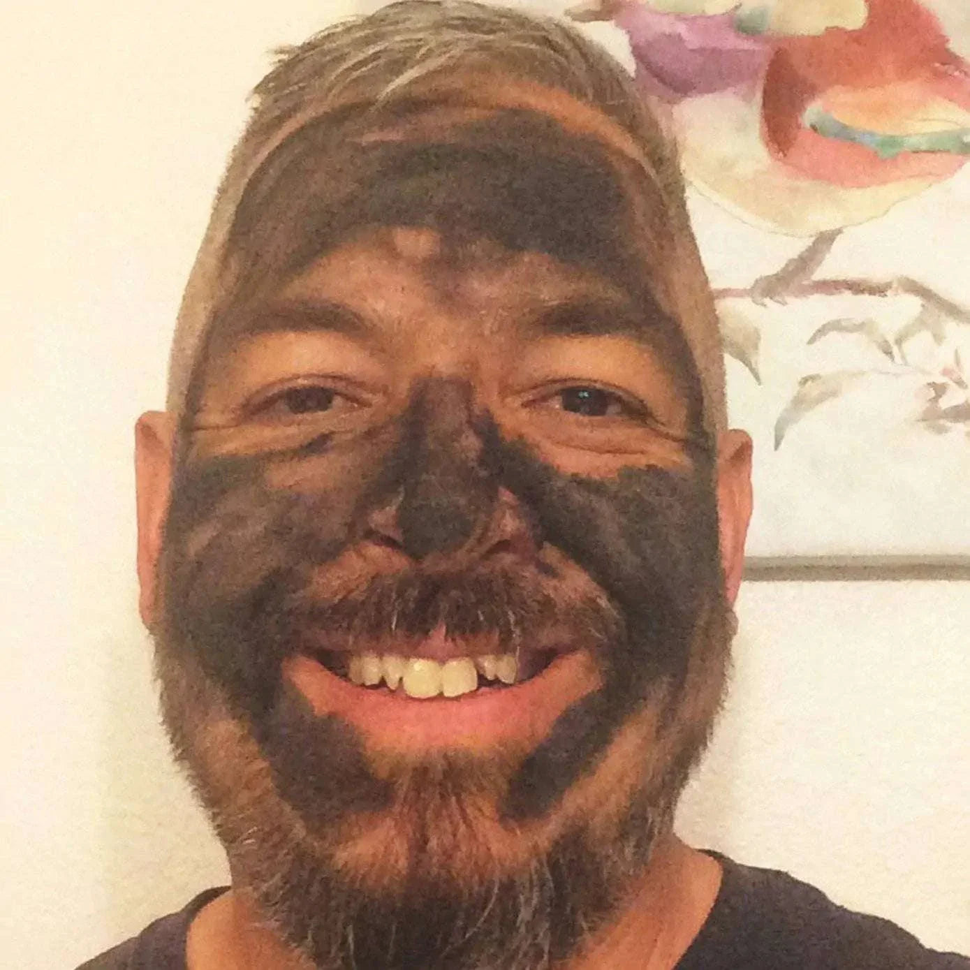 smiling man with organic activated charcoal face mask applied for detox and purification