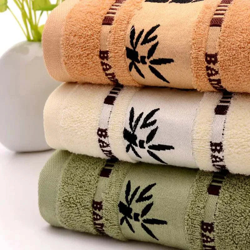 stacked eco-friendly bamboo fiber towels in khaki, white, and green colors with black bamboo design and soft texture