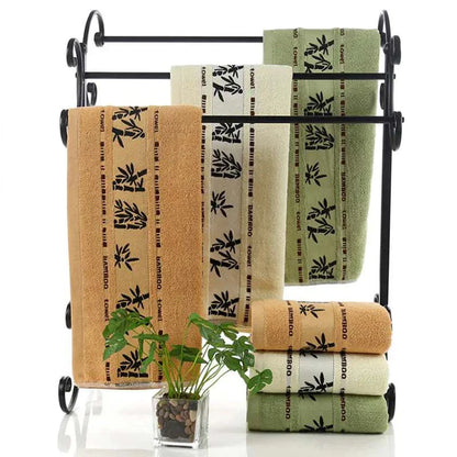 Set of thick bamboo fiber towels in khaki, green, and white with bamboo pattern on black metal towel rack
