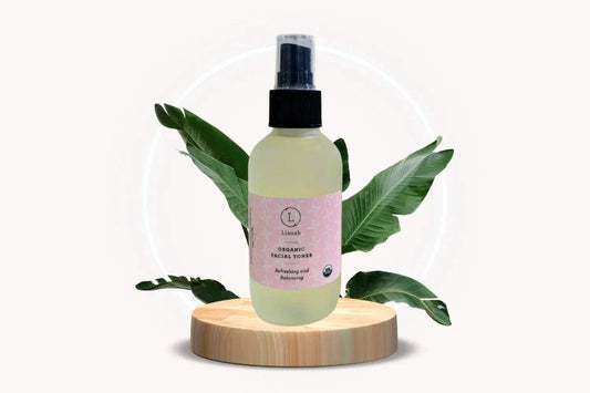 Organic Facial Toner bottle with pink label on wooden stand and green leaves background